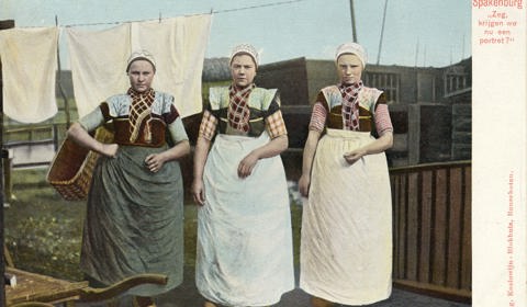 Drie meisjes in klederdracht, bezig met de was in de tuin van een huis te Spakenburg