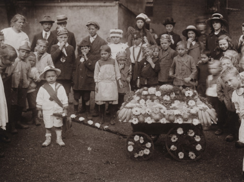 Kinderen met versierde kar in het Oranjepak tijdens Koninginnedag